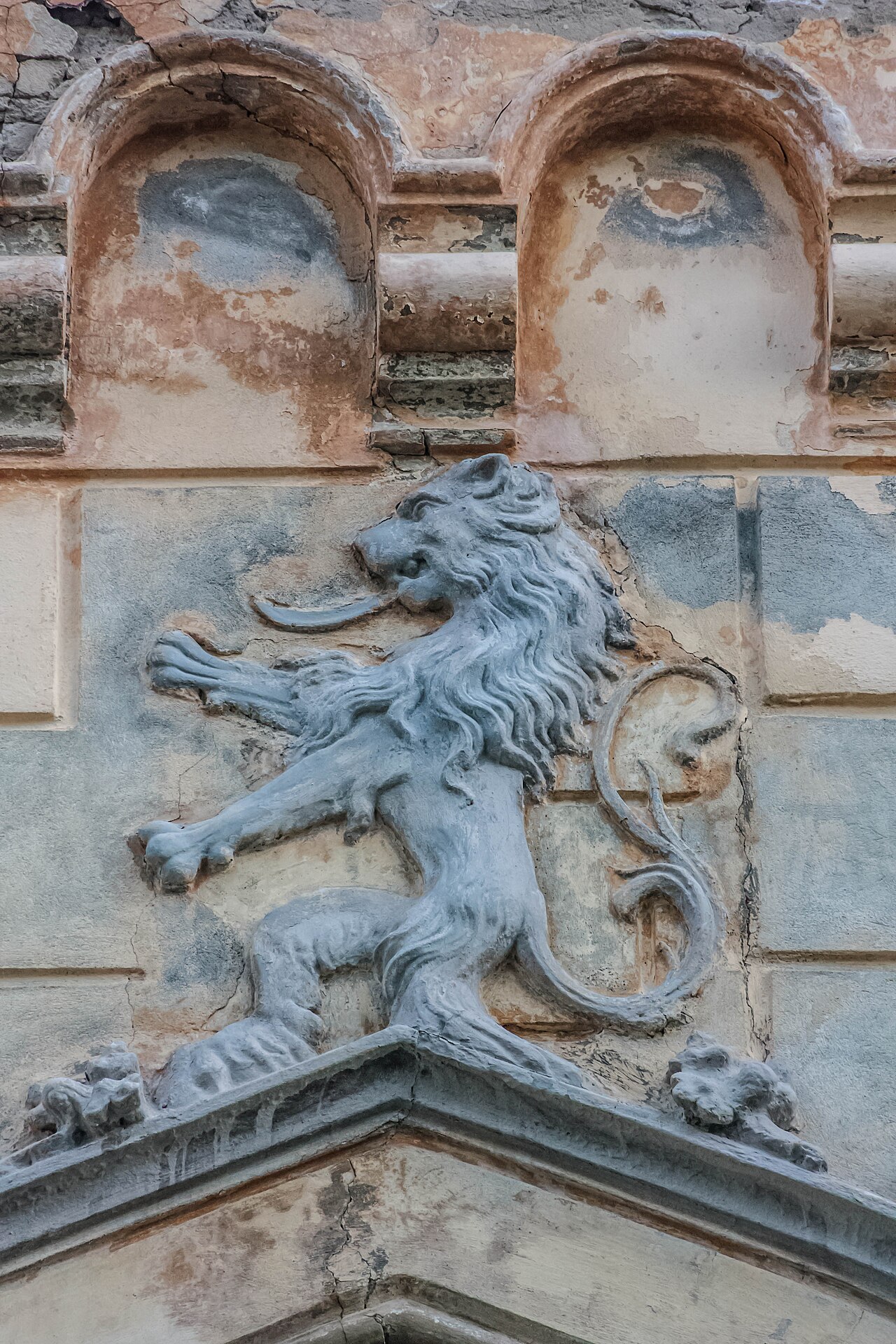 Sculptură figurativă deasupra unui ancadrament, cu uzura pietrei vizibilă.