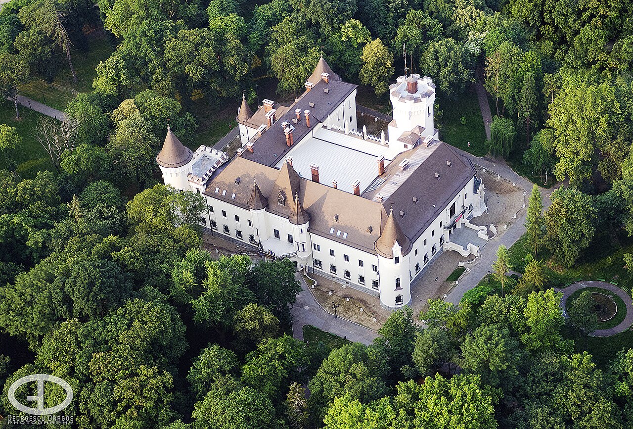 Vedere aeriană oblică a castelului: aripi, acoperișul curții acoperite, turnuri și coșuri.