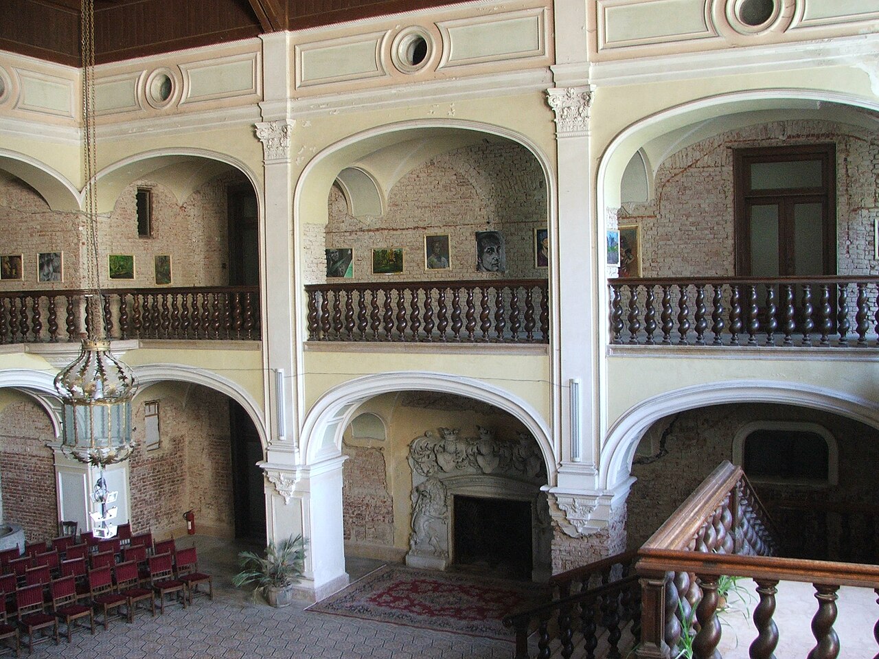 Holul văzut de la galeria superioară: arcade, parapete și scara interioară.