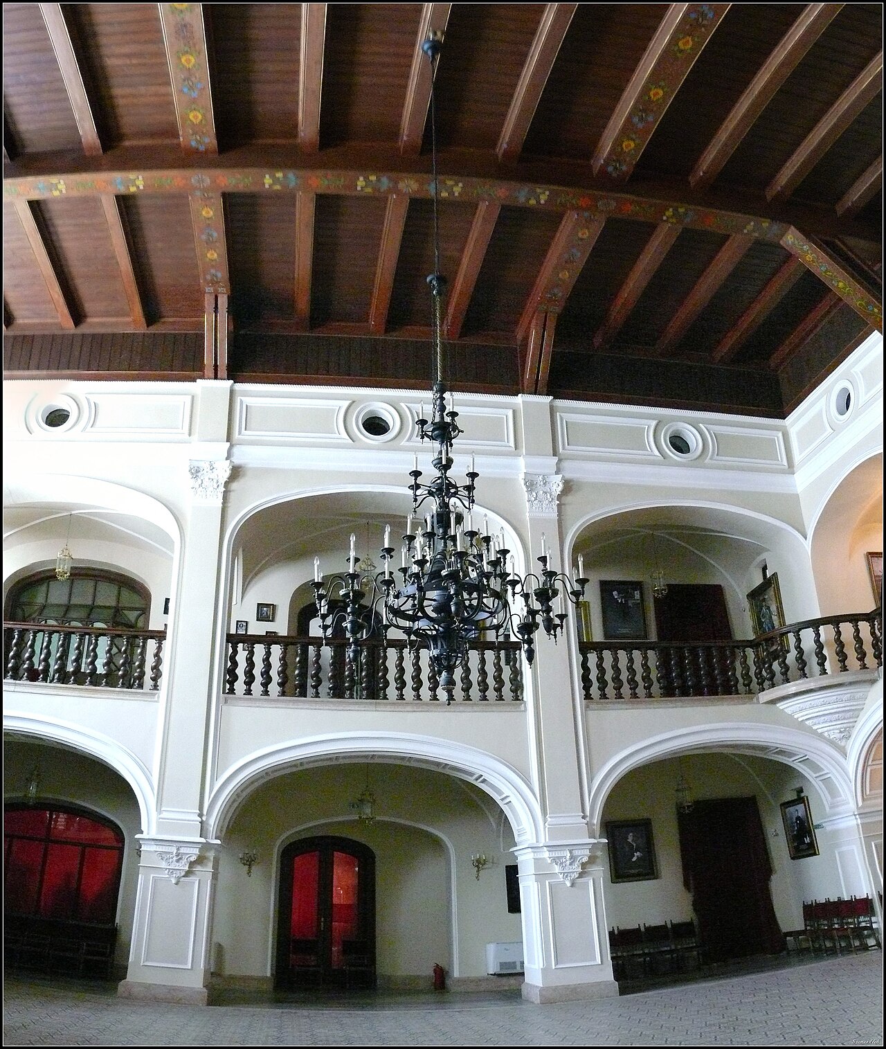 Plafonul din grinzi, candelabrul și galeriile holului central, în contraplonjeu.