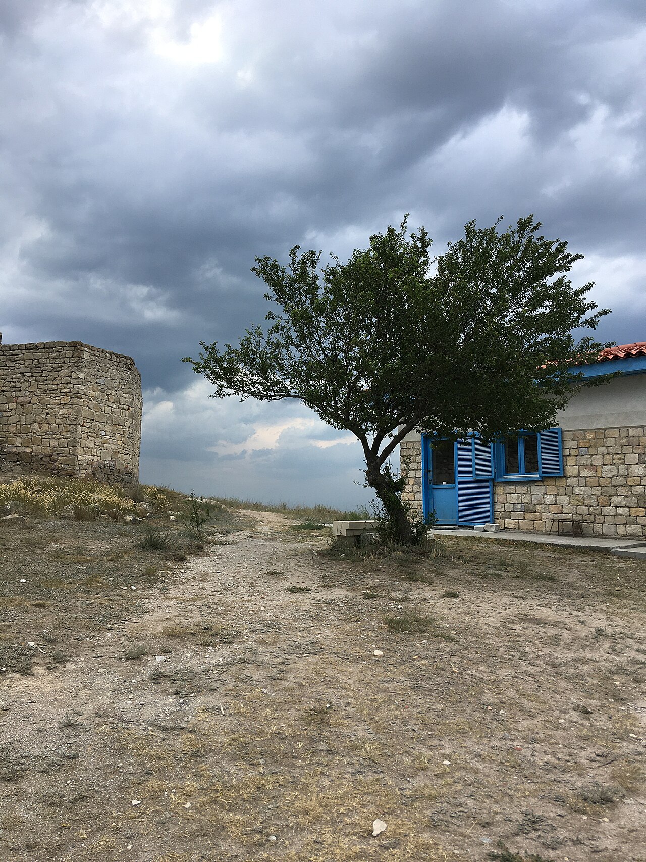 Curte cu turn și arbore, diferențele de nivel ale solului și zidurile fragmentare.