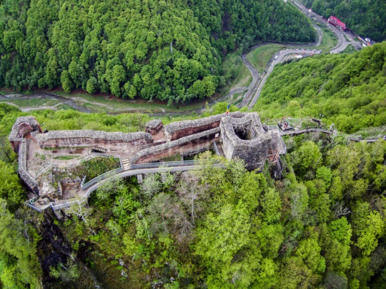 Vedere aeriană oblică apropiată: incinta lungă, donjonul, turnurile și pasarelele interioare.