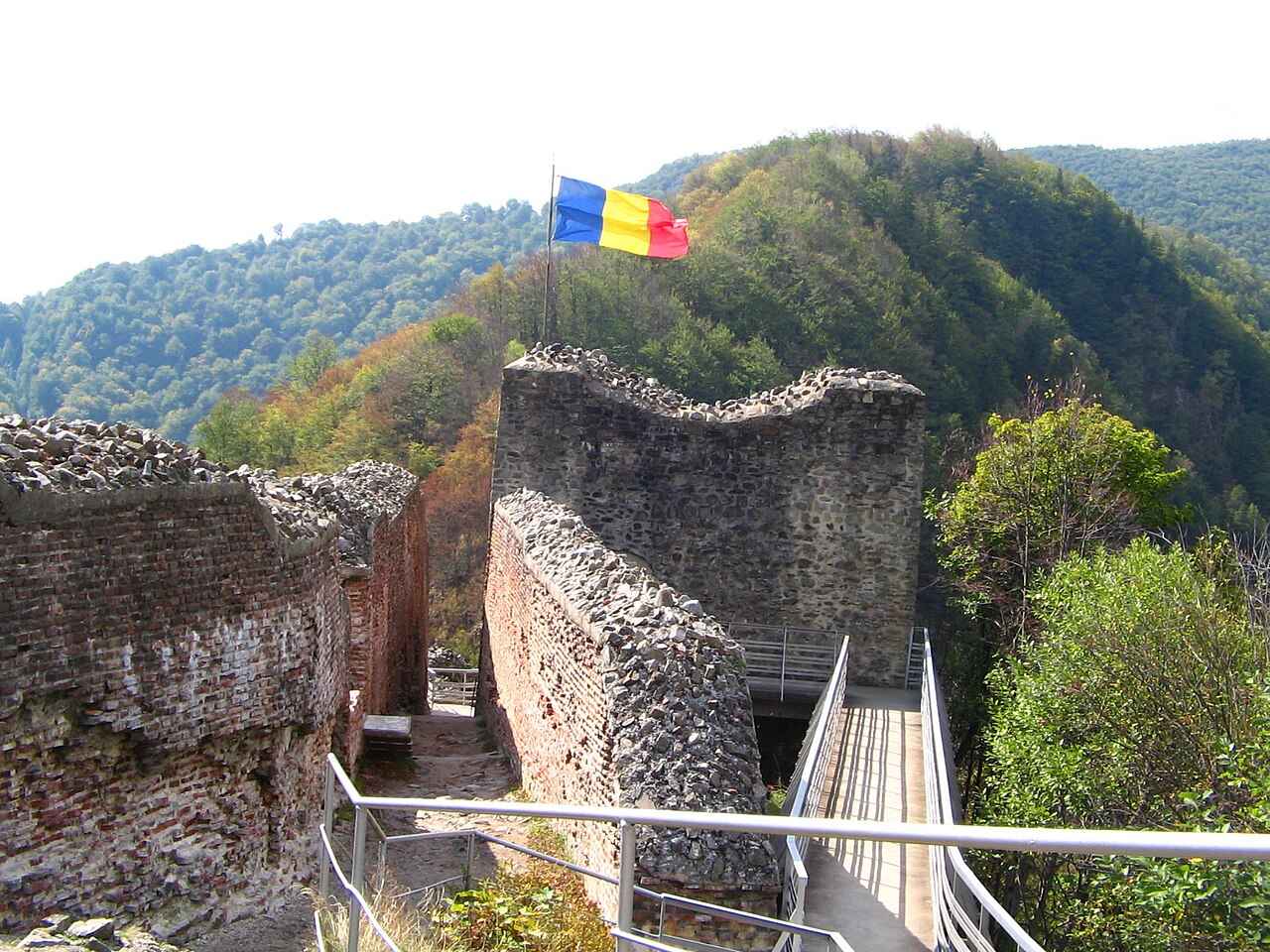 Donjon și ziduri interioare văzute de pe platformă, cu balustrade în prim-plan.