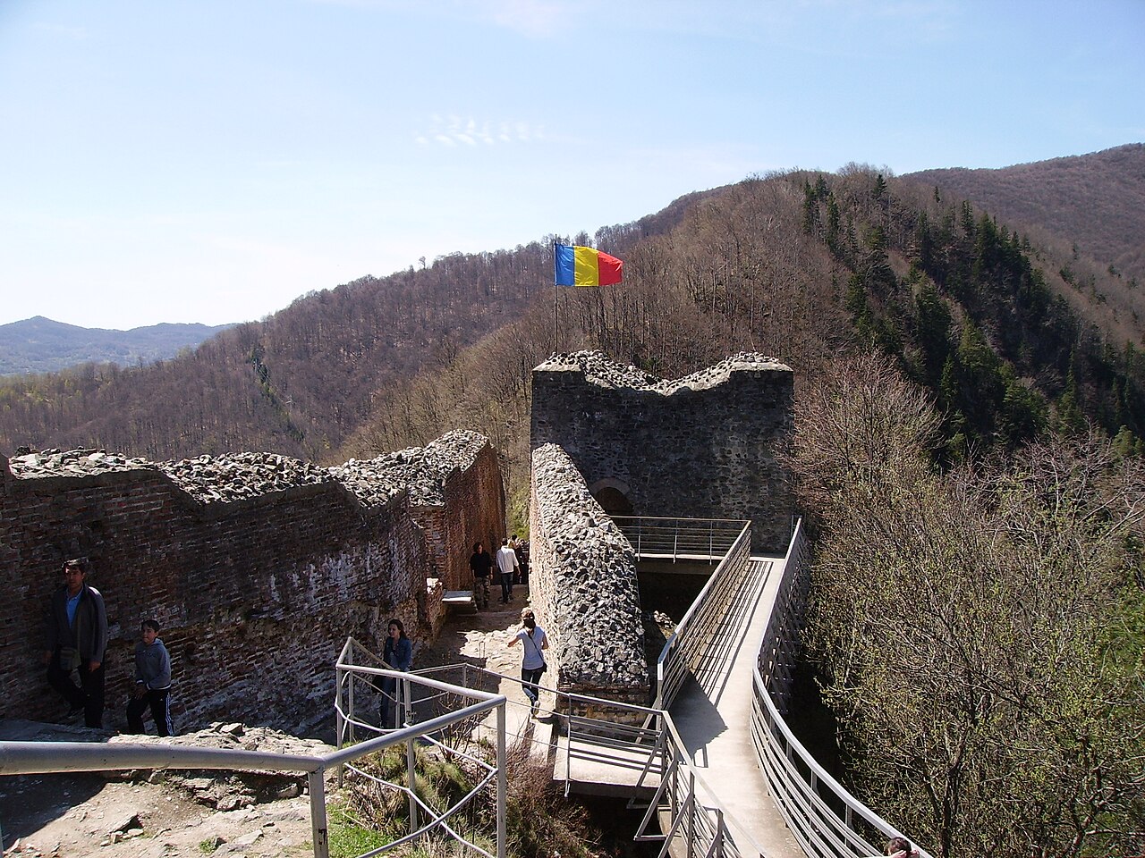 Curtea și zidurile dinspre platforma de vizitare, cu traseele metalice vizibile.