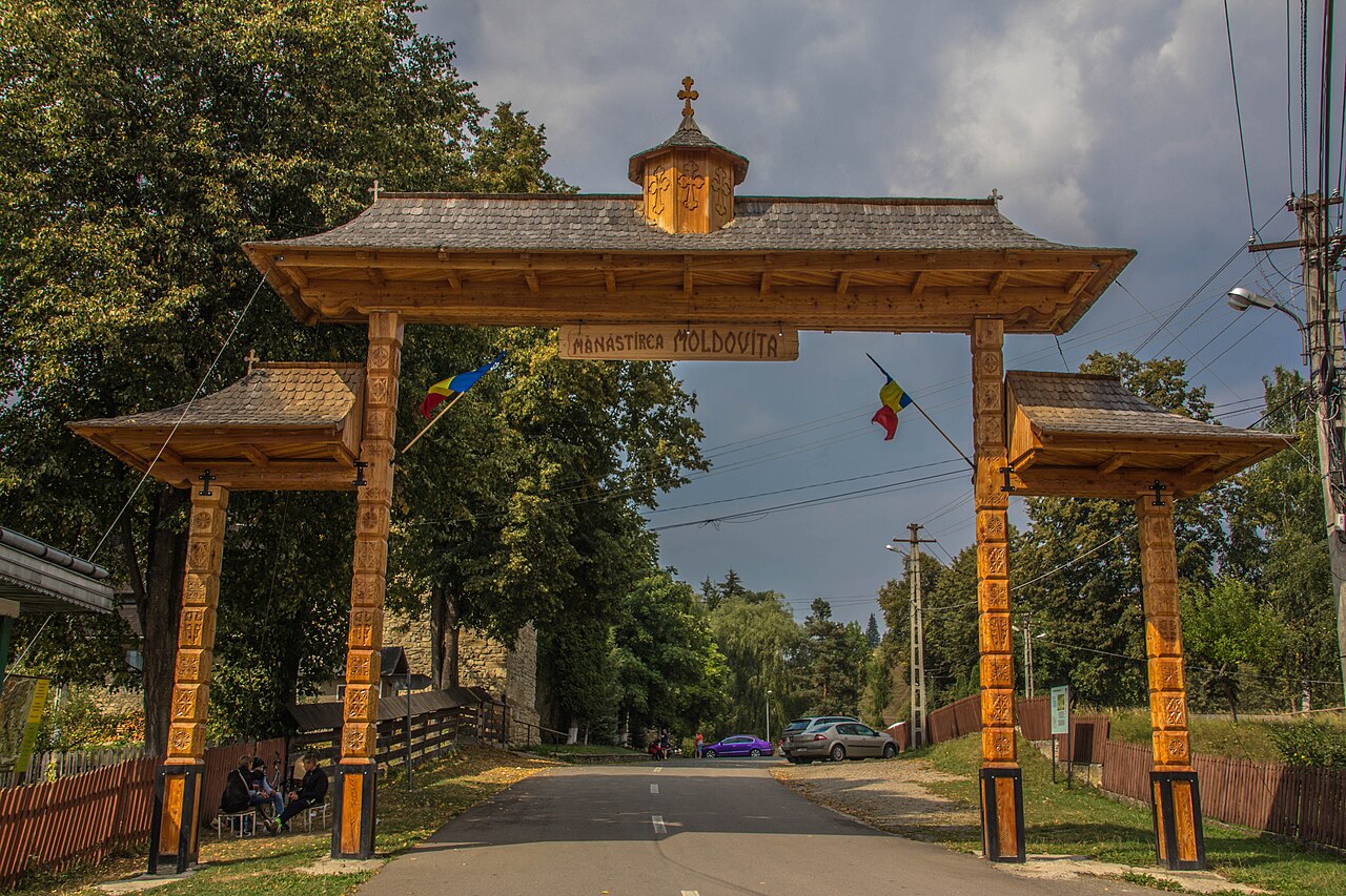 Poarta de lemn din exteriorul incintei, cu stâlpi și acoperiș.