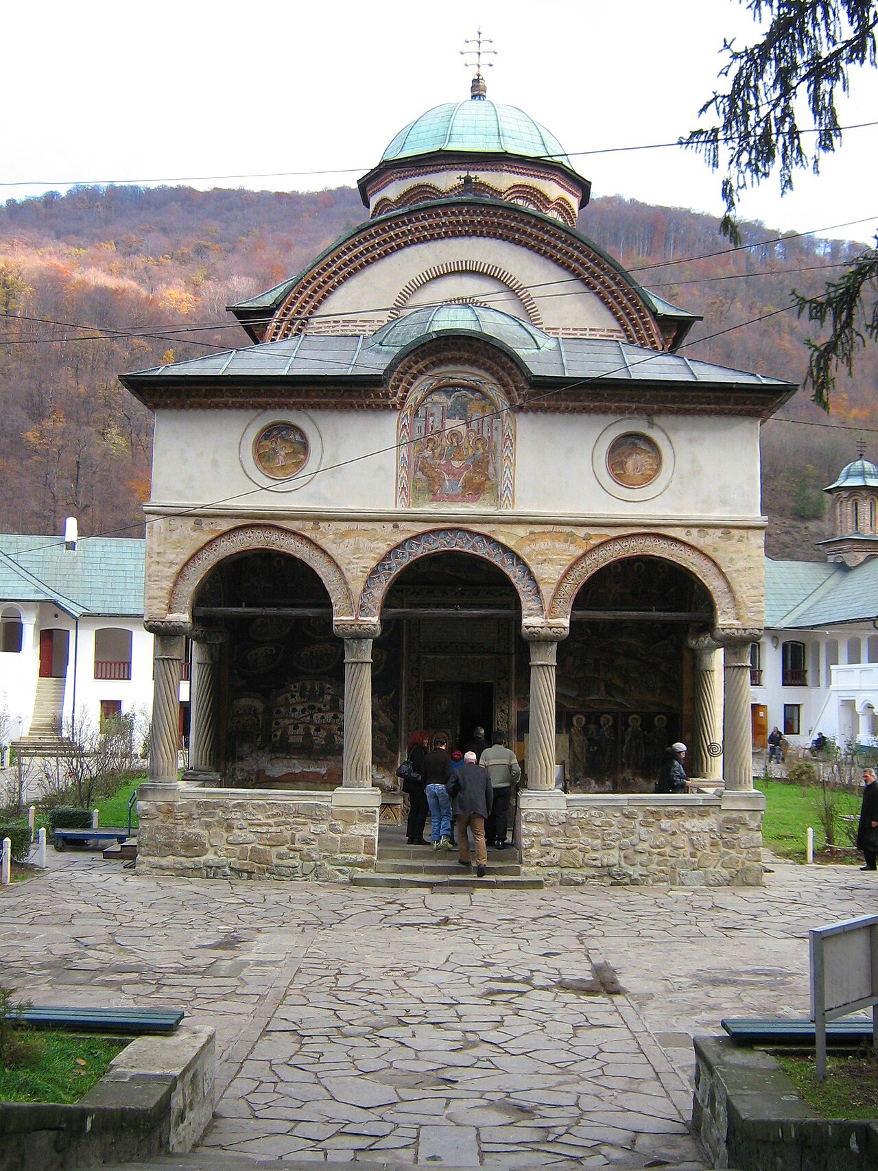 Pridvorul văzut frontal: arcade, coloane și fronton.