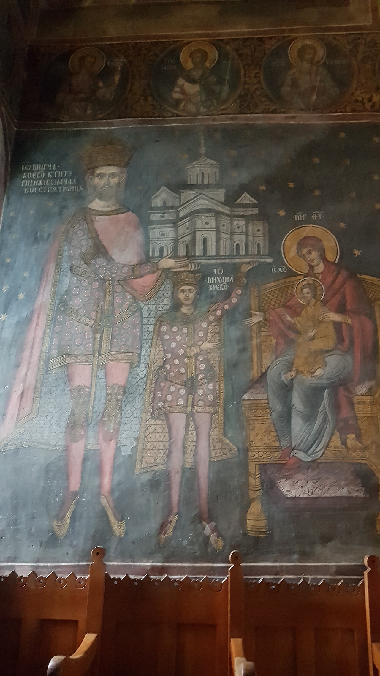 Perete interior pictat și mobilier; iluminarea limitează lizibilitatea.