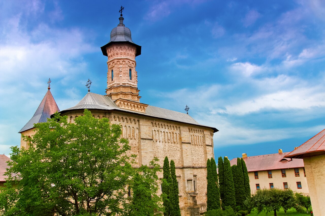 Biserica mare Pogorârea Sfântului Duh: volum înalt, absidă, turlă sculptată și incintă.