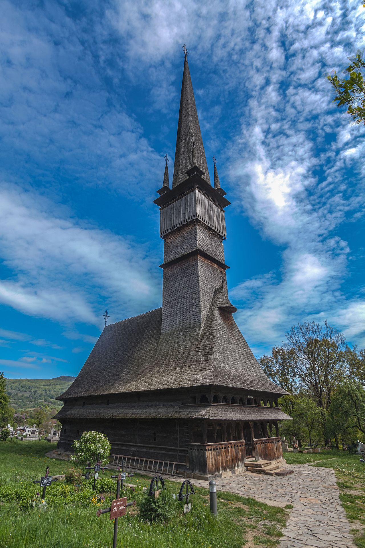 Biserica UNESCO Sfinții Arhangheli, vedere oblică: turn înalt, pridvor pe două niveluri și acoperiș cu dublă poală.