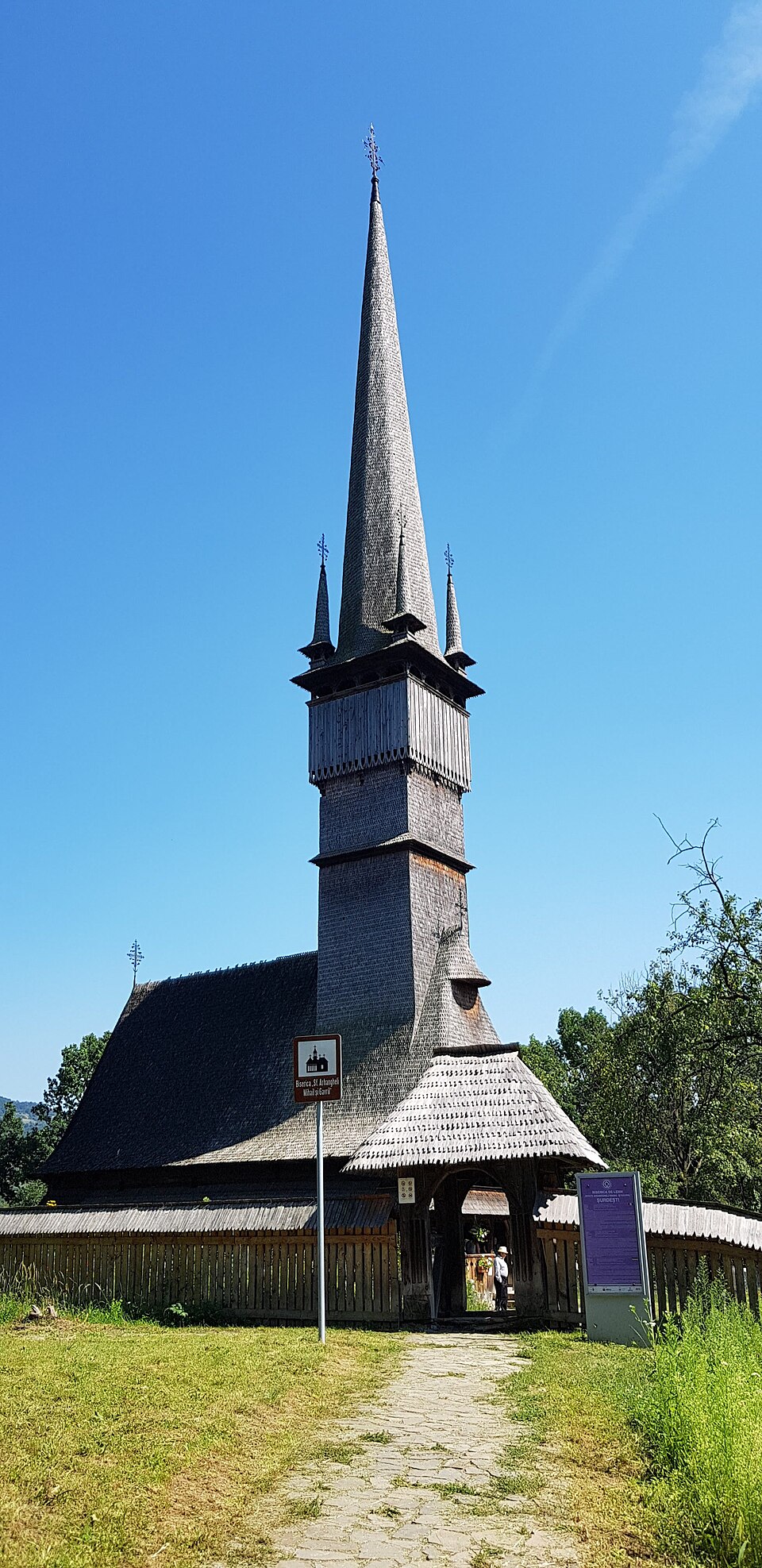 Biserica văzută din curte, cu turnul, învelitoarea și pridvorul.