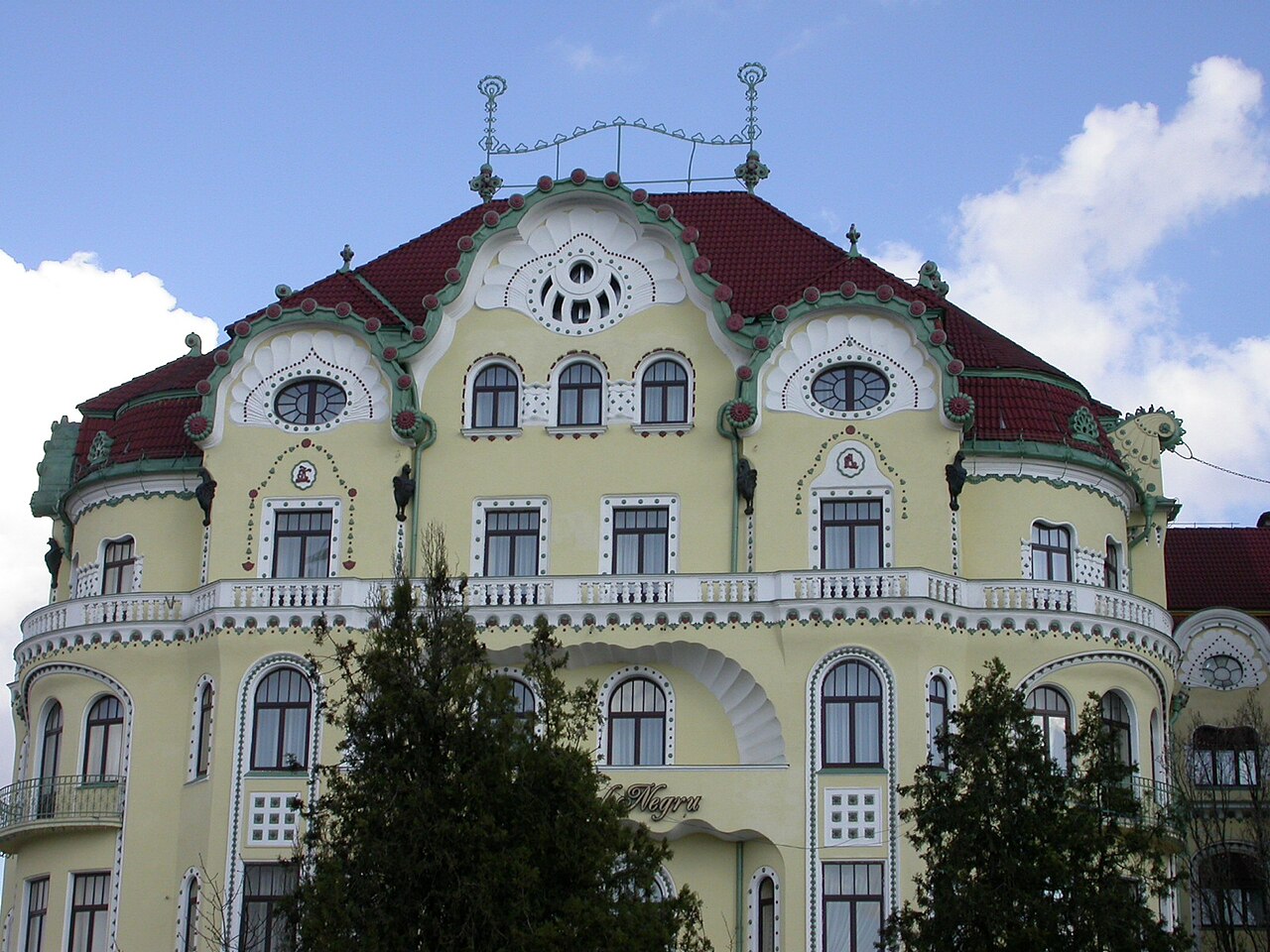 Frontonul curbat al corpului principal, ferestre și ornament circular.