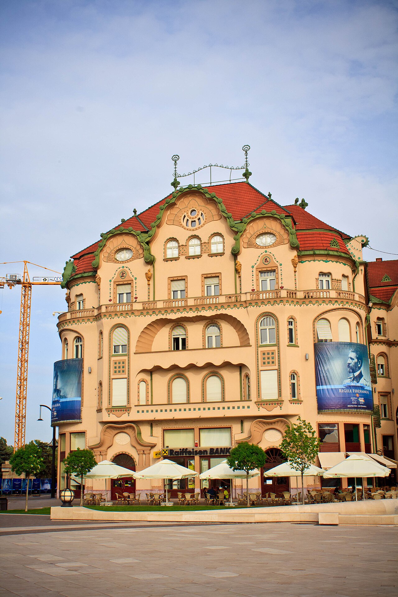 Corpul cu frontonul lat, balcoanele și parterul comercial, în vedere apropiată.