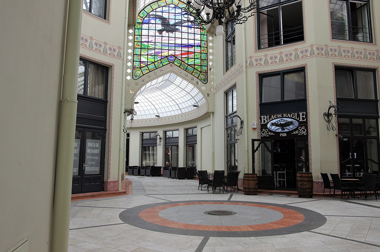 Pardoseala circulară a nodului, intrări comerciale și vitraliul din fundal.
