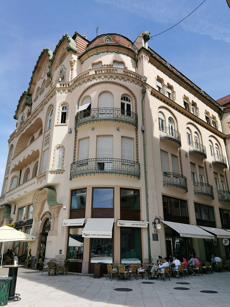 Fațadă laterală de colț, balcoane și goluri arcuite.