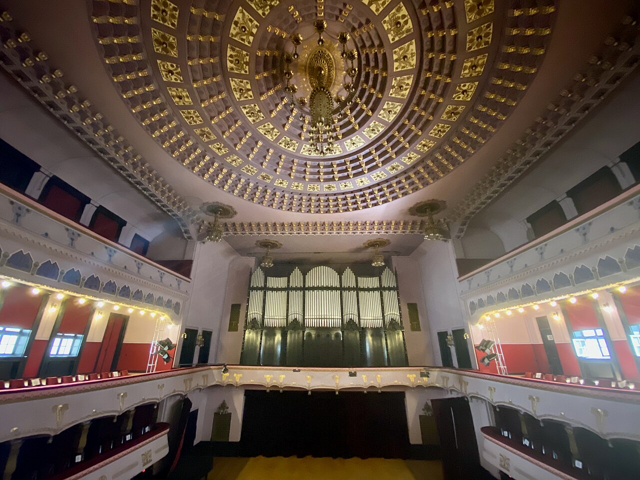 Sala de concerte dinspre scenă: balcoane, plafon și corpul central de iluminat.