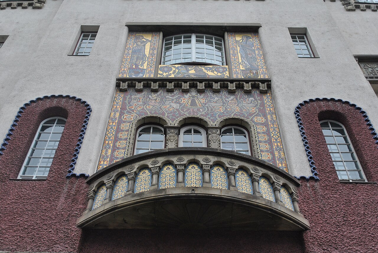 Balcon ornamental curbat și ferestrele din spatele său.