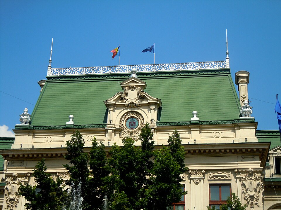 Frontonul central cu ceas și panta mansardată a acoperișului.