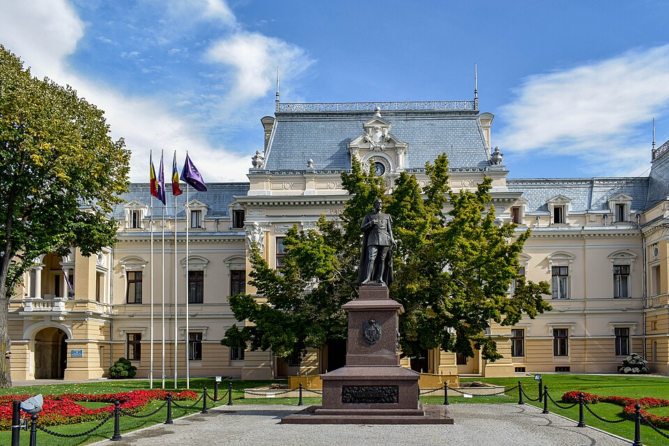 Fațada principală cu învelitoarea gri și statuia din față.