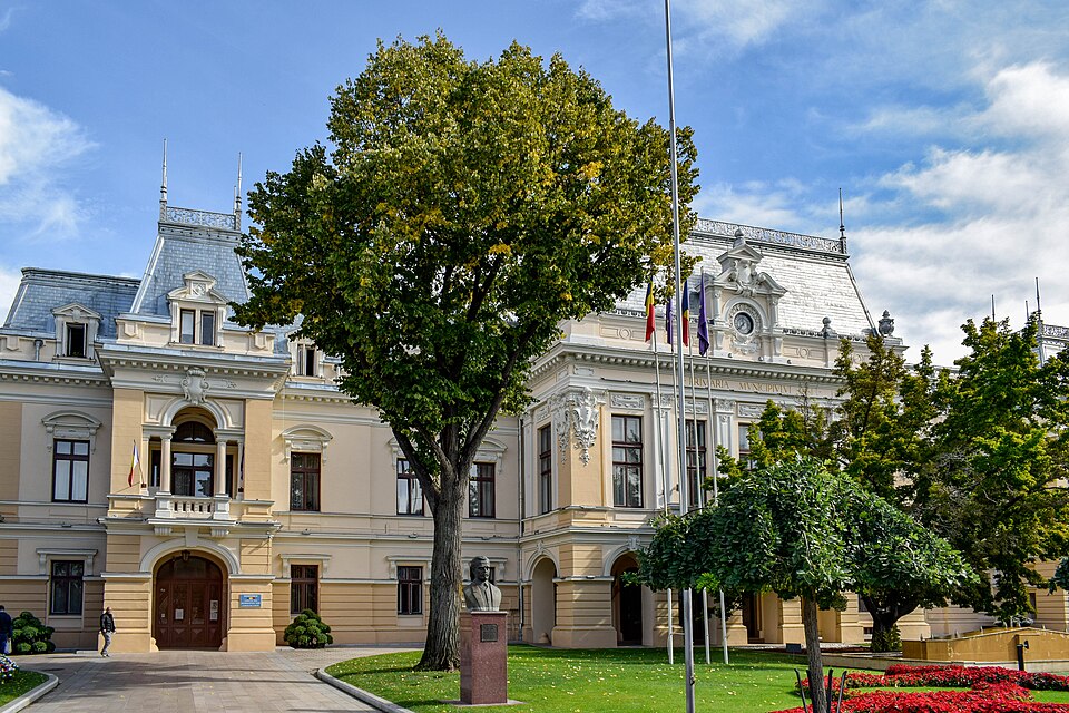 Aripa opusă cu ferestre, portal arcuit și streașină; arborele ascunde corpul central.