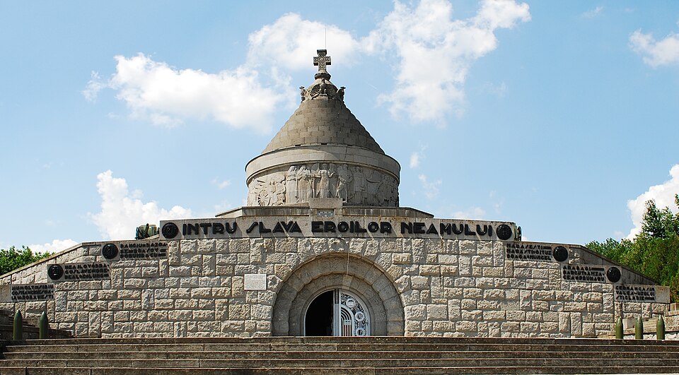 Intrarea principală aproape frontală, cu asizele de piatră și inscripția.