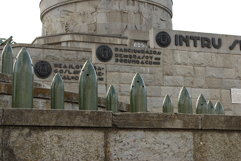 Parapetul terasei cu obuze decorative, frontispiciul și basorelieful în fundal.