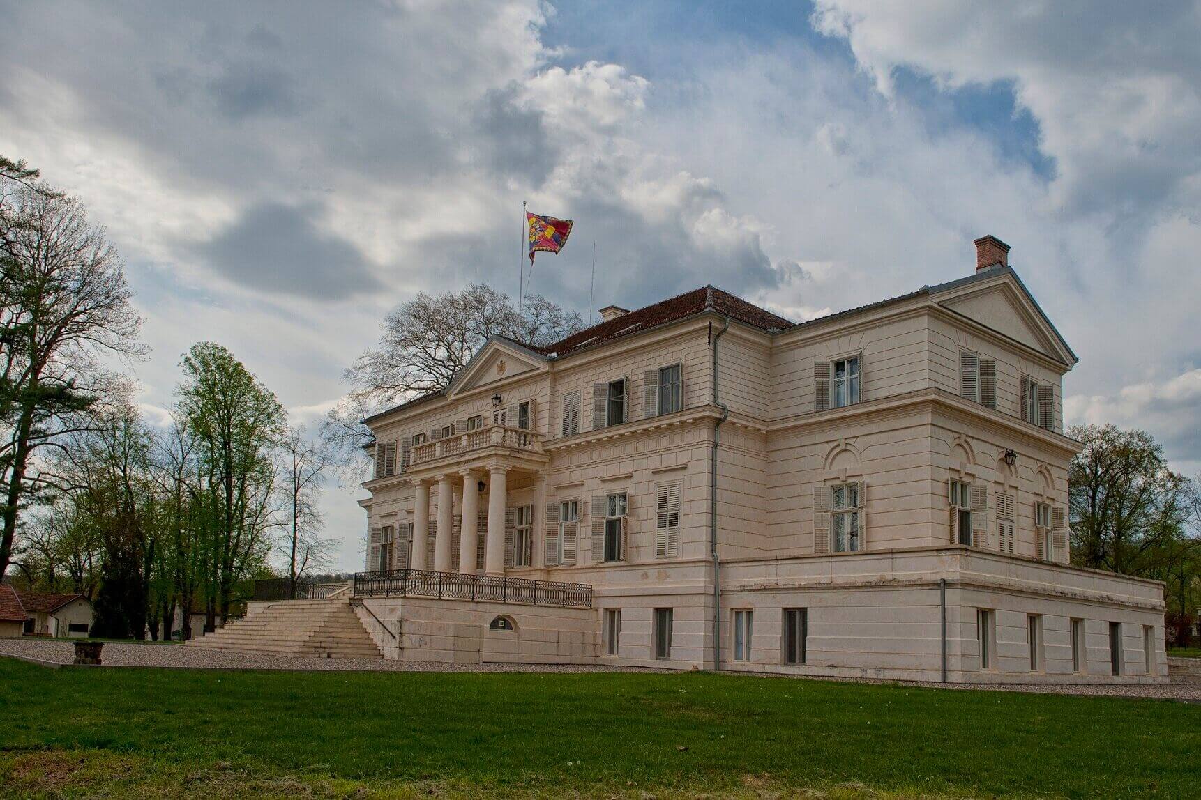 Castelul restaurat, vedere oblică din parc: fațadă lungă, risalit, soclu și acoperiș.