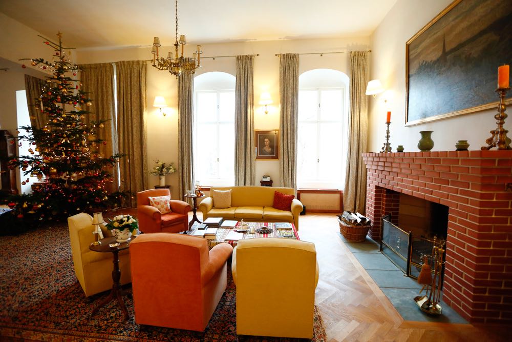 Salonul mare cu ferestre, șemineu și tavan; decor sezonier de Crăciun.