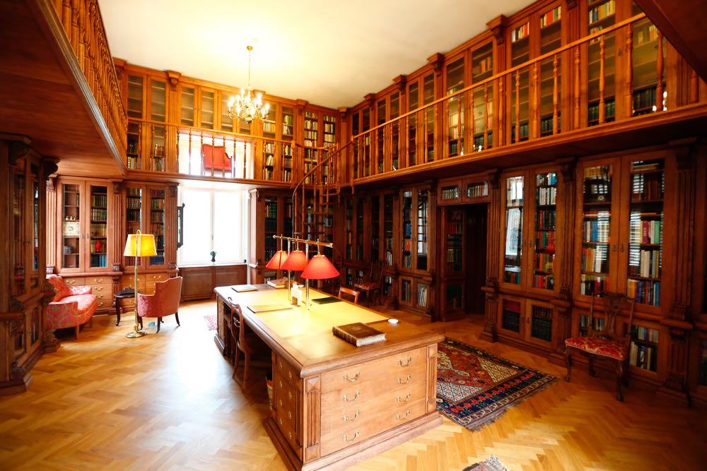 Biblioteca restaurată, cu corpuri de lemn pe pereți și masă centrală.