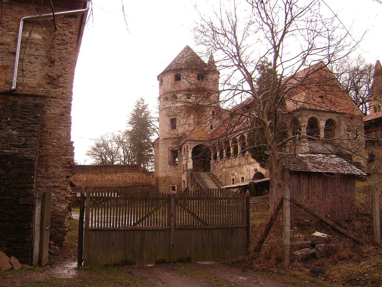 Turnul și loggia privite printr-un acces al curții, cu vegetație fără frunze.