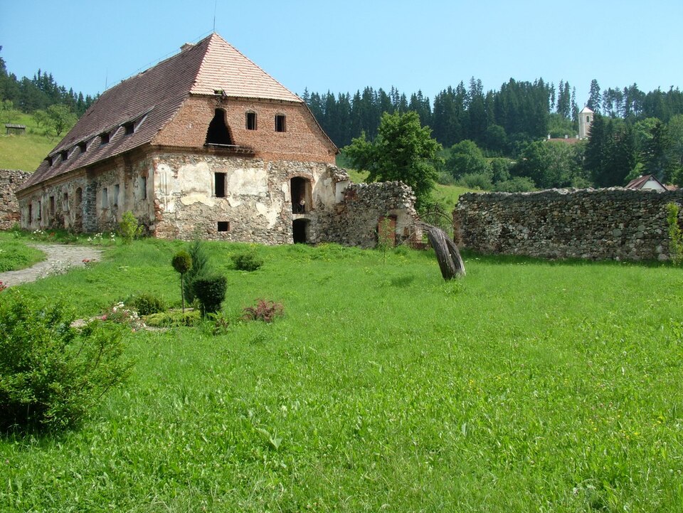 Corpul cu acoperiș lung și lucarne, privit oblic din curte.