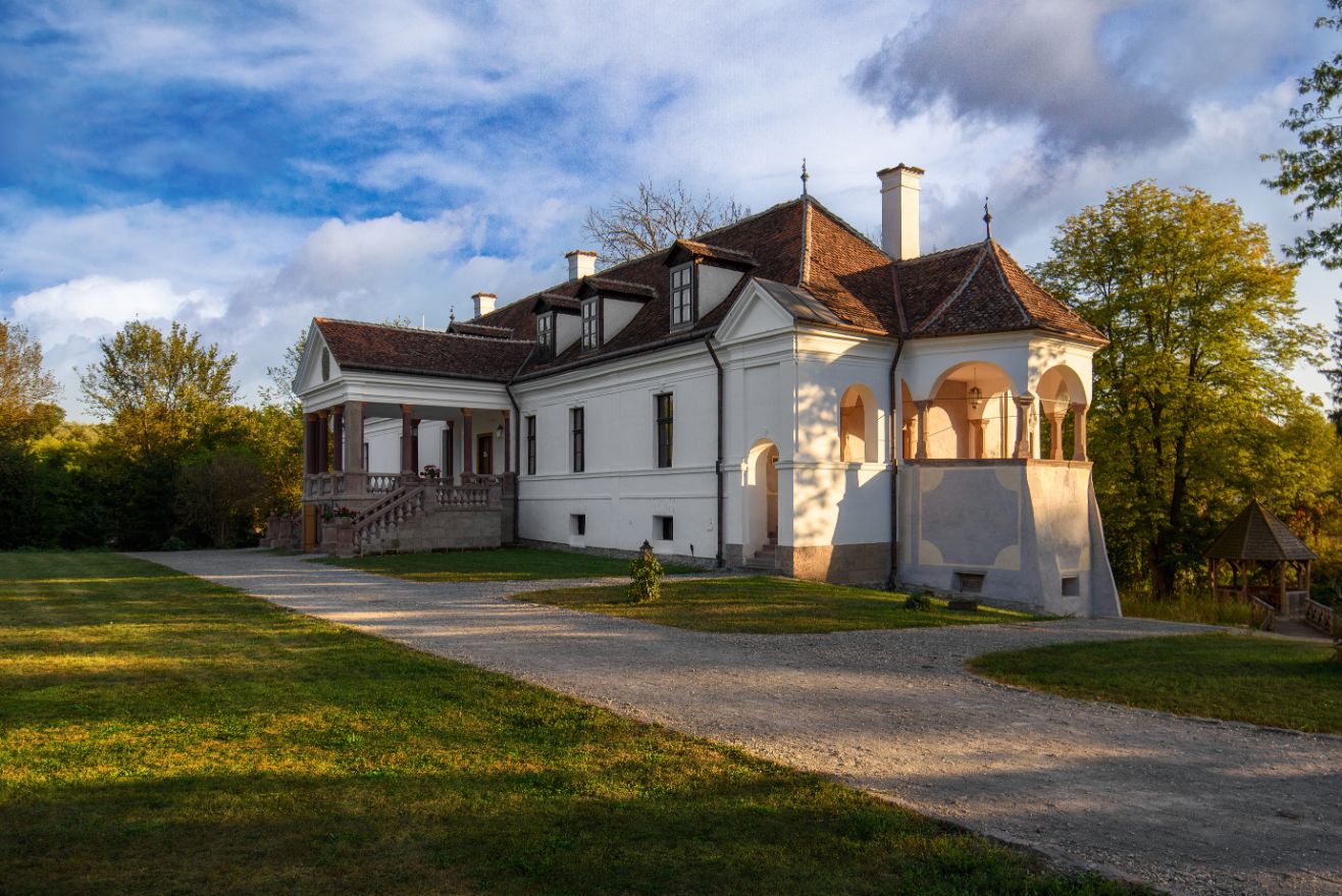 Castelul restaurat privit oblic: portic central, volum lung, pavilion lateral și lucarne.
