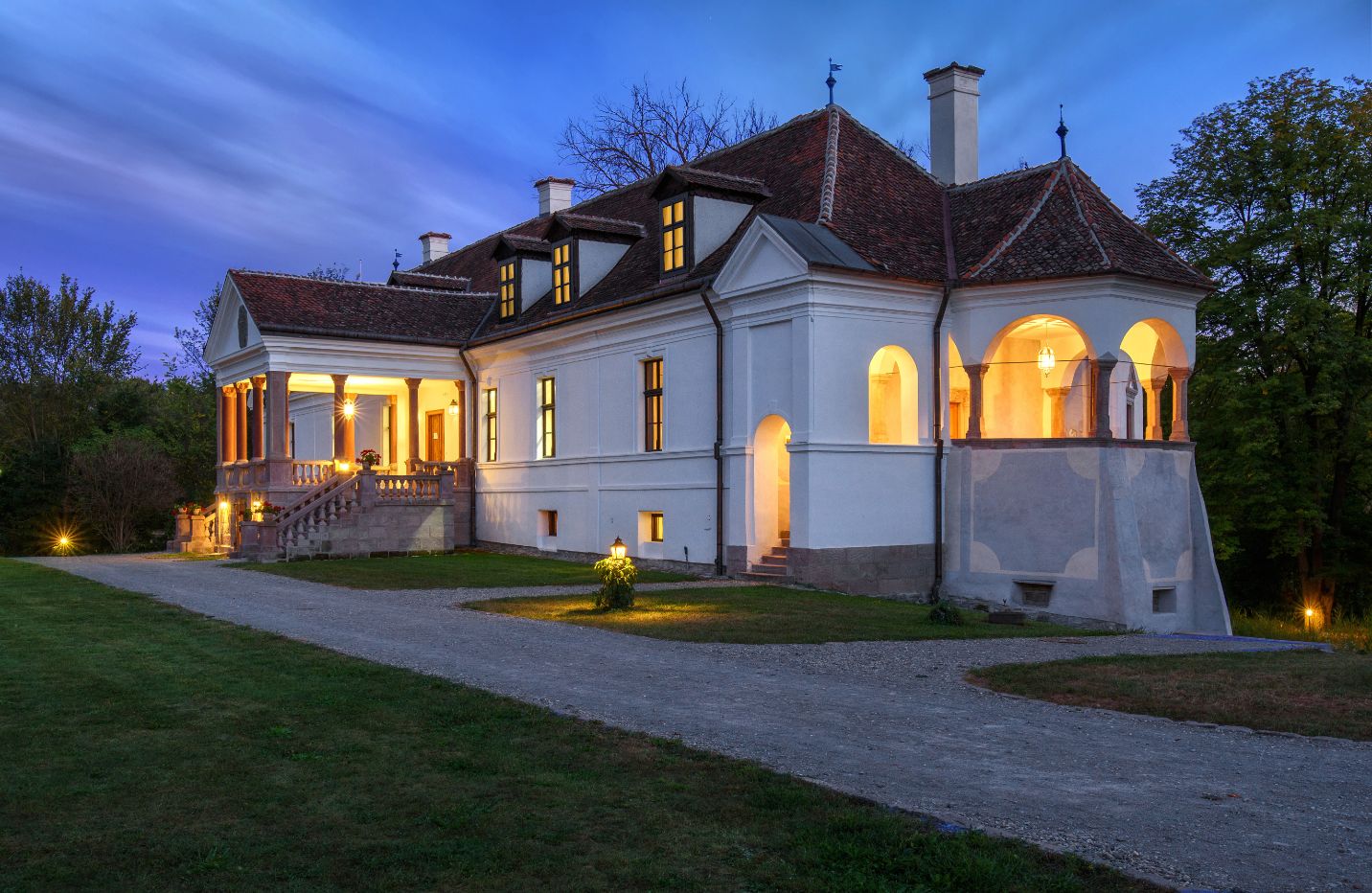 Castelul iluminat seara; geometria porticului și pavilionului lateral.