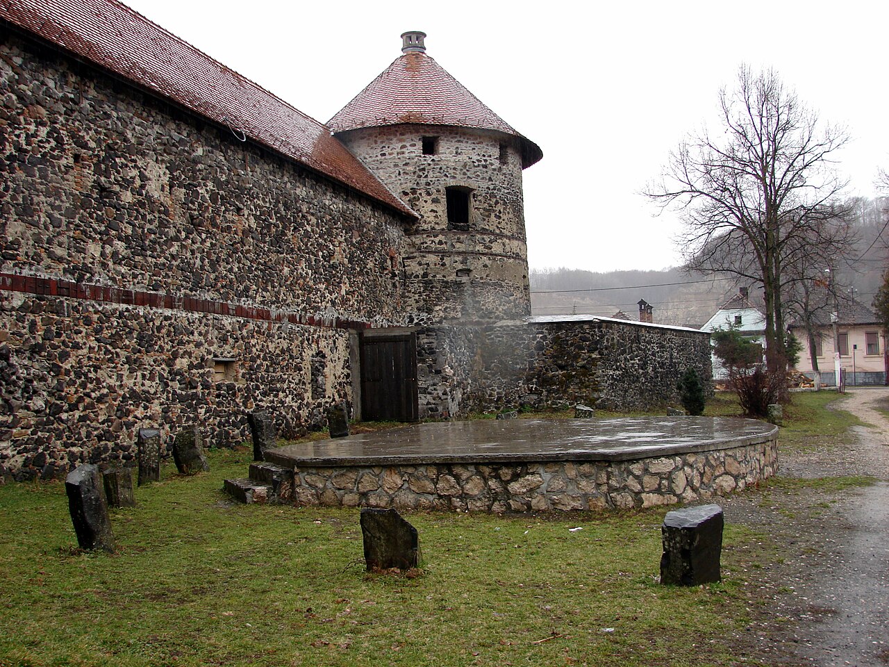 Zidul exterior de piatră și turnul rotund de colț.