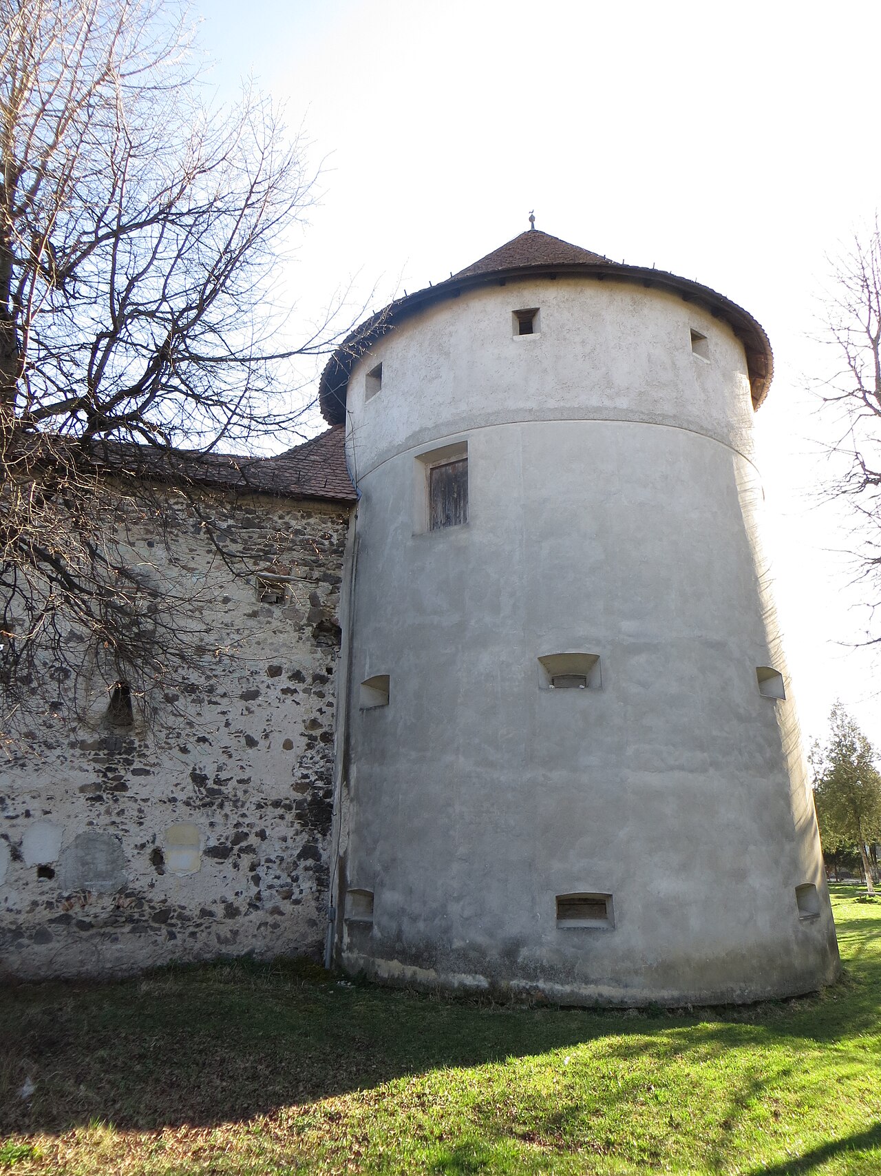 Turn rotund de colț: soclu, goluri și acoperiș conic.