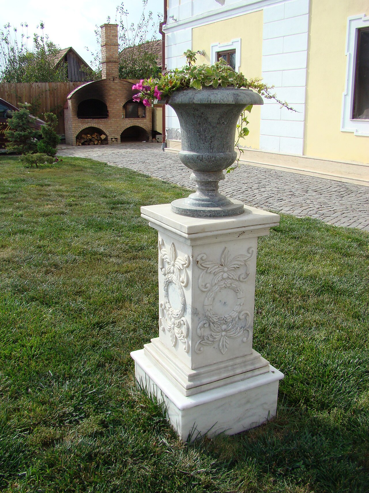 Vas decorativ pe soclu și racordul fațadei cu grădina.