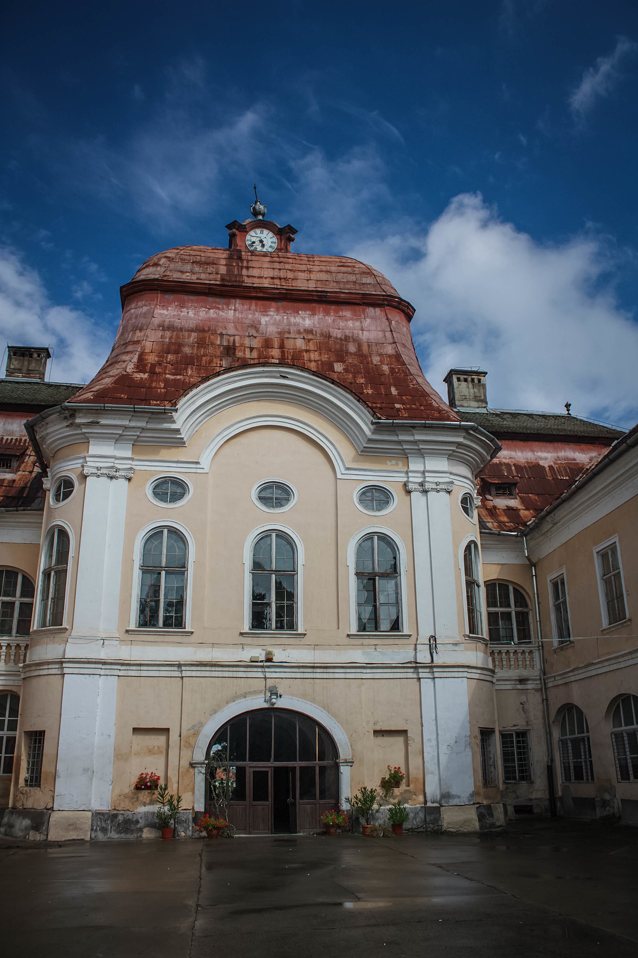 Pavilionul central, ferestre arcuite și acoperișul cu ceas, văzute frontal.