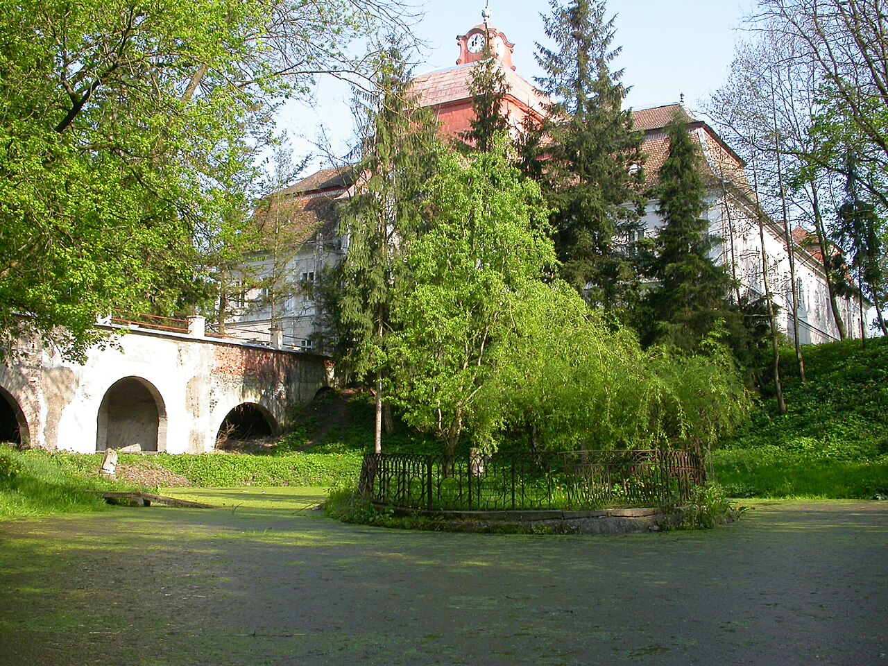 Fațada opusă și accesul cu arcade, dinspre parc, parțial mascate de arbori.