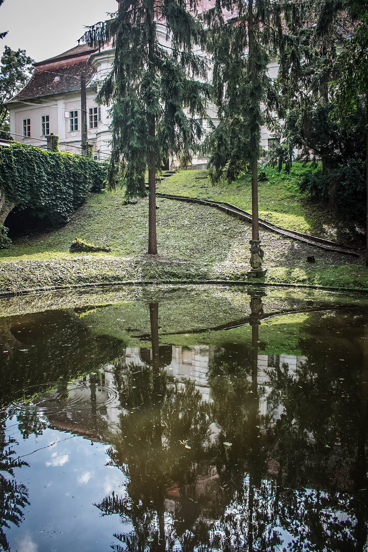 Fațada dinspre parc, reflexia în apă și accesul pe pod.