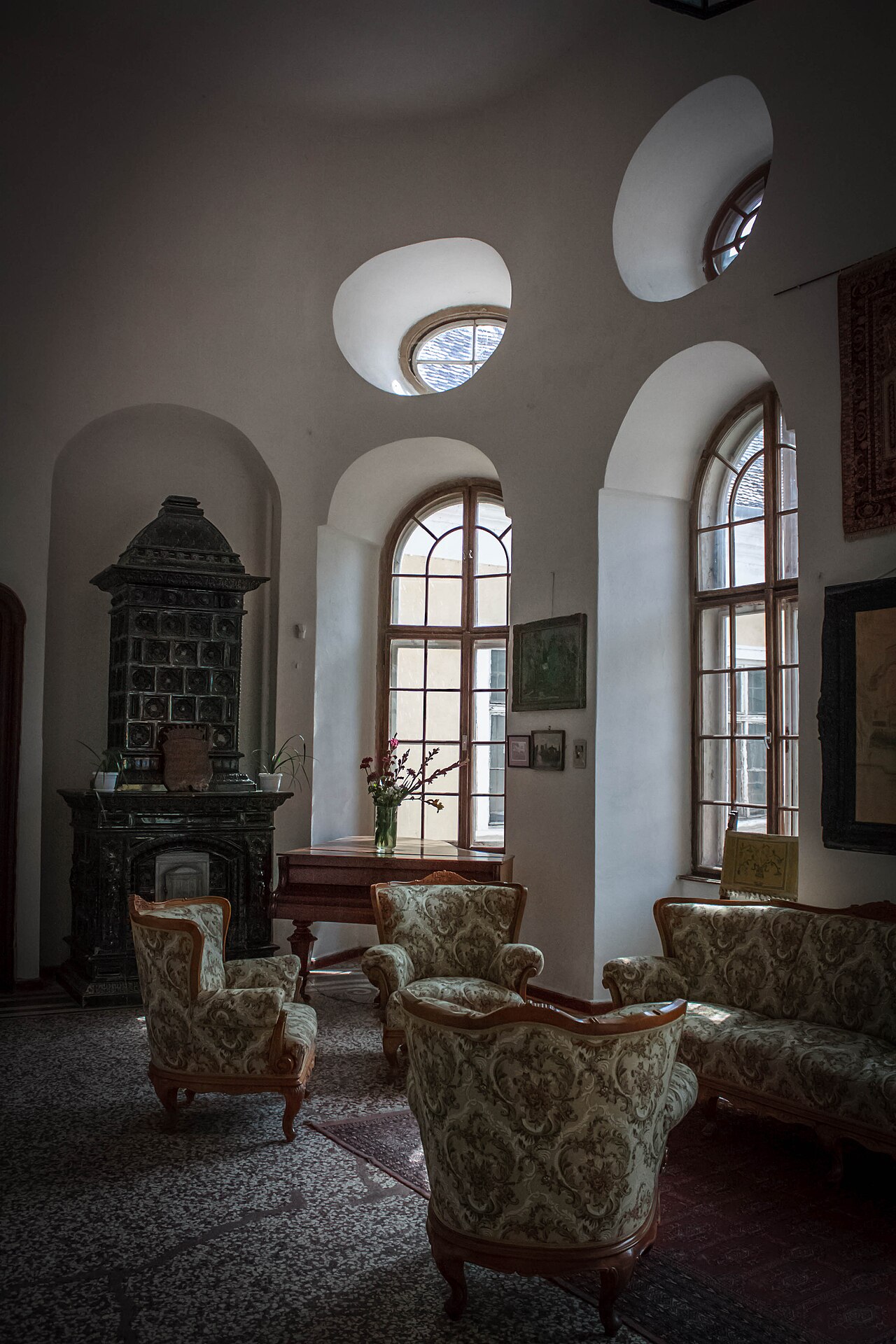 Colțul sălii cu ferestre, mobilier și decor de perete.