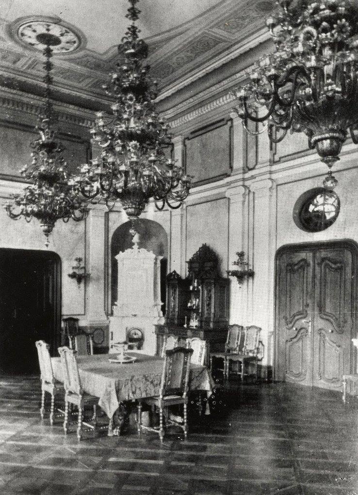 Fotografie istorică a salonului, în jurul anului 1900: lambriuri, stucaturi, candelabre și pardoseală; mobilier diferit de starea recentă.