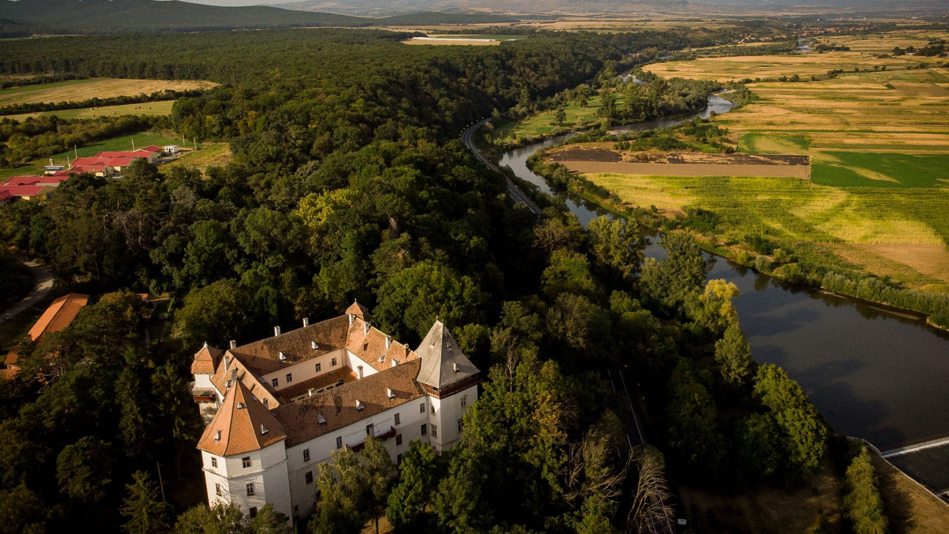 Fotografie aeriană de ansamblu, cu castelul, parcul și valea Mureșului.