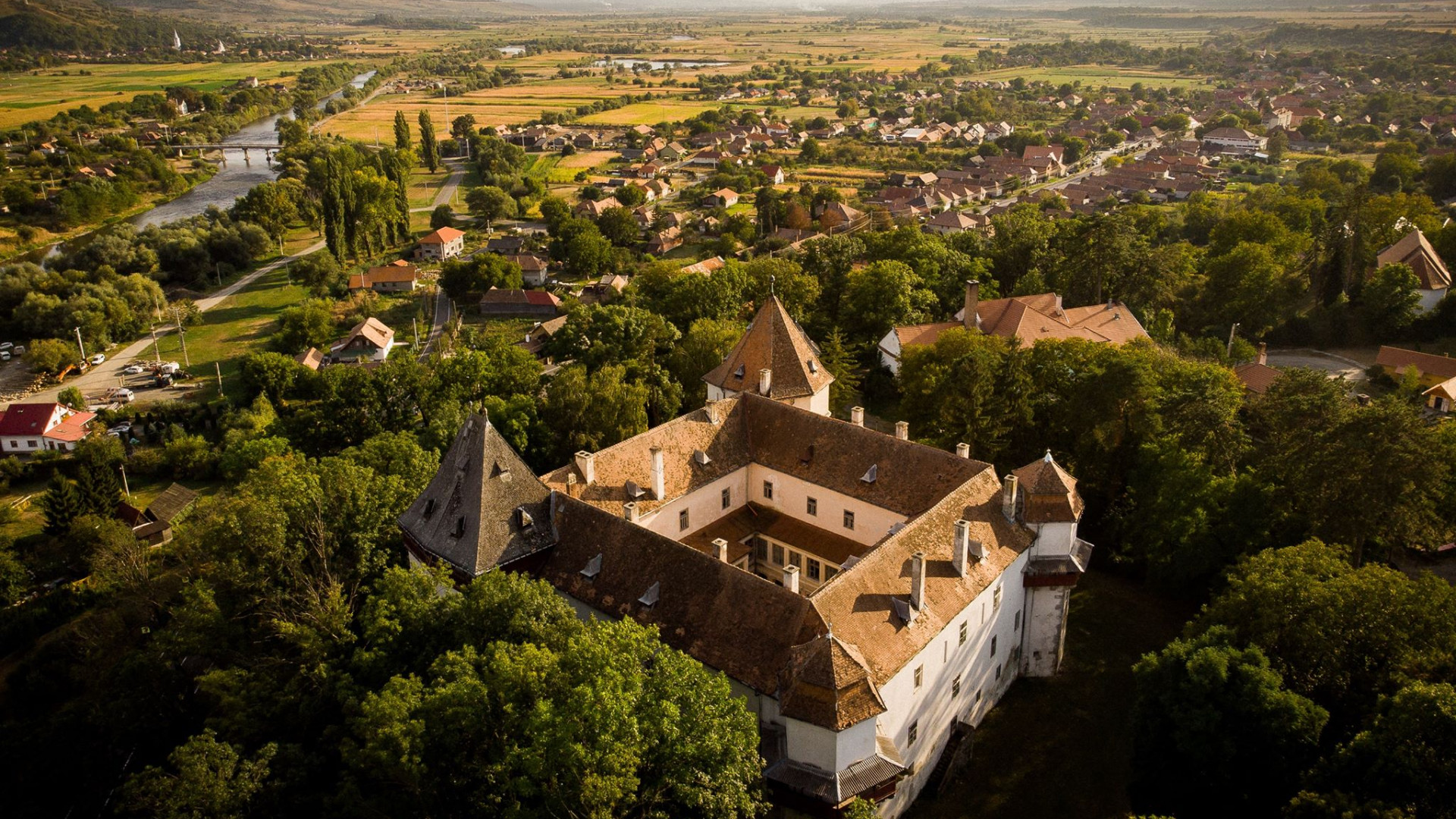 Fotografie aeriană cu curtea, turnurile și satul în fundal.