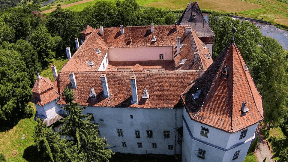 Fotografie aeriană apropiată a acoperișurilor, turnurilor și curții, creditată CNIPT Reghin.