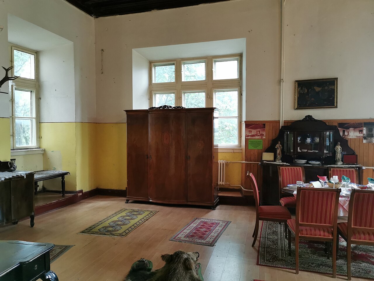 Colțul unei încăperi: dulap, ferestre și grinzi.