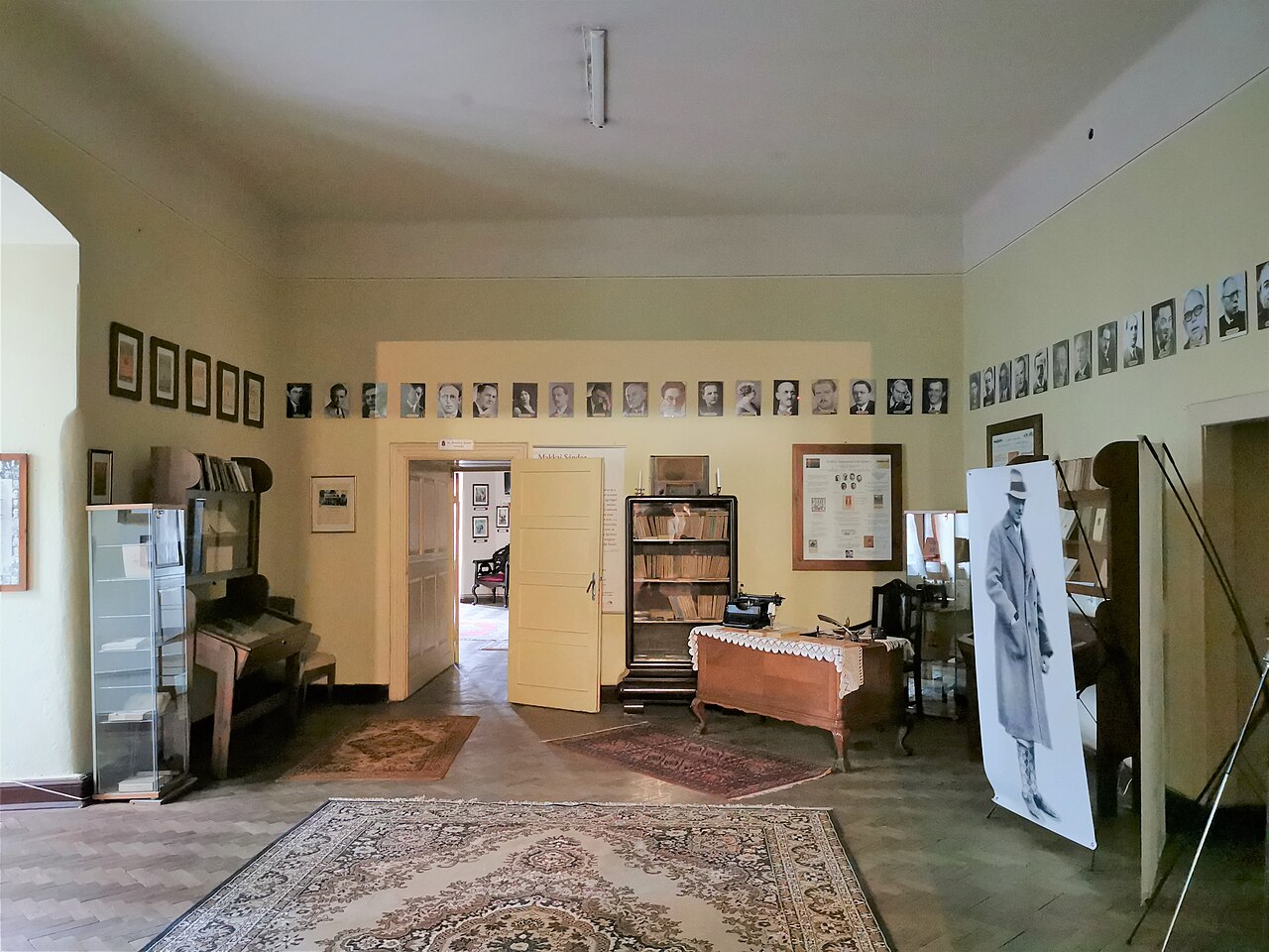 Cameră memorială cu ferestre, pereți și mobilier de expunere.