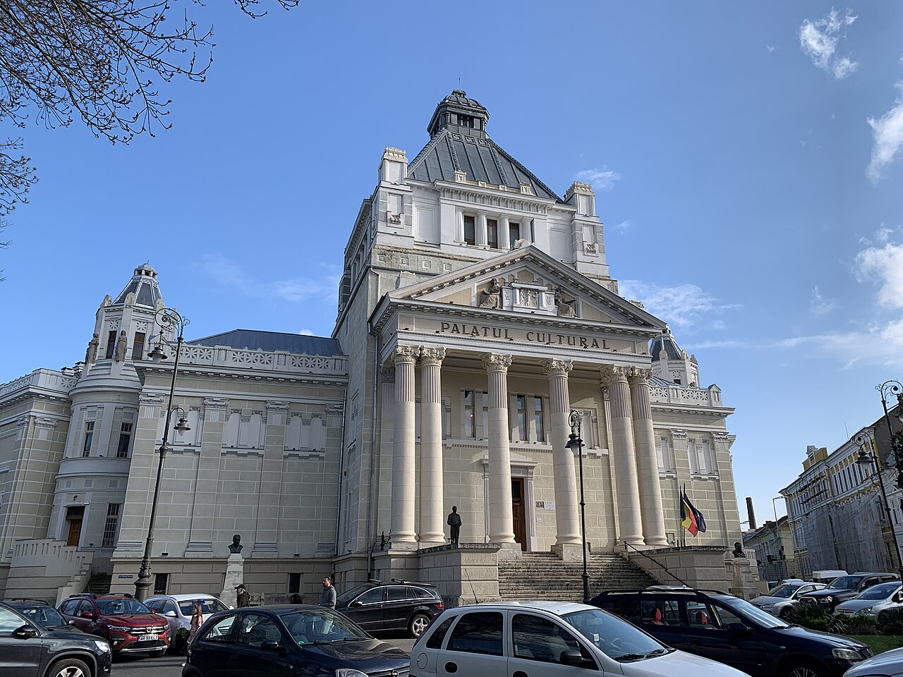 Palatul privit oblic din piață: portic, turn și volum lateral.