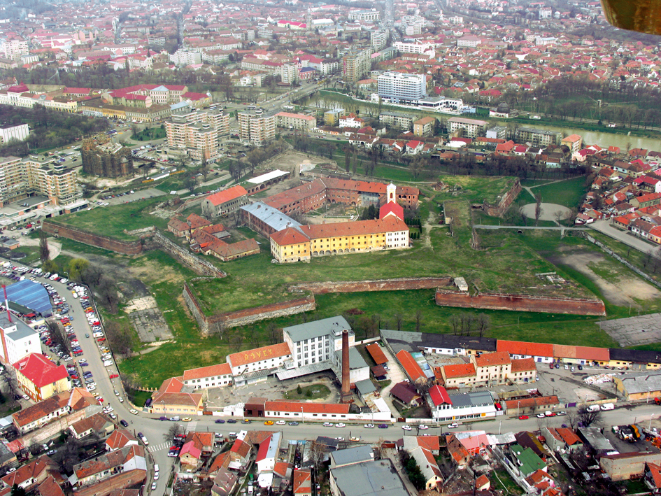Fotografie aeriană oblică a cetății: conturul pentagonal, bastioane și corpurile din incintă.