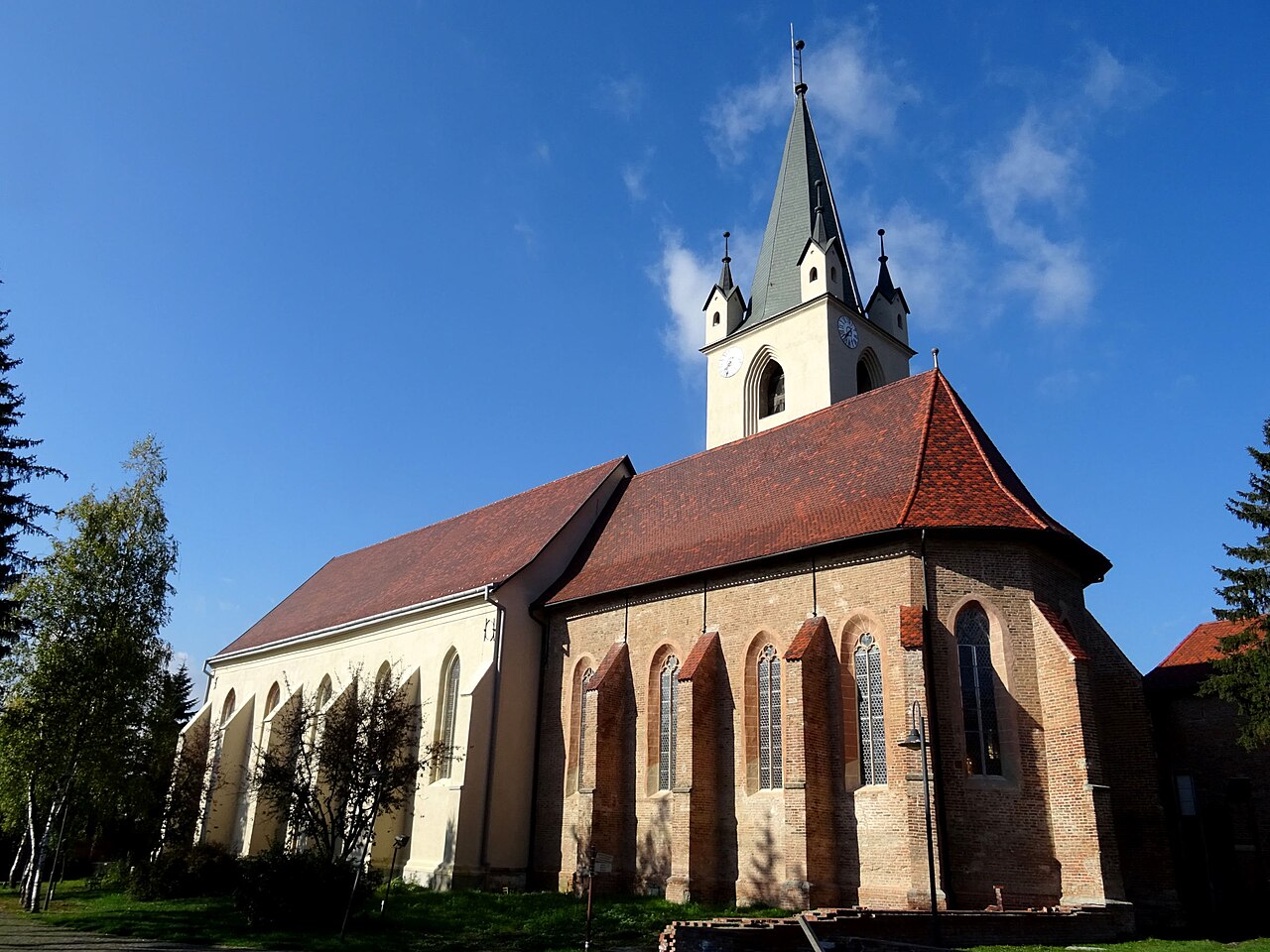 Biserica văzută dinspre corul poligonal, cu contraforturi și turn.