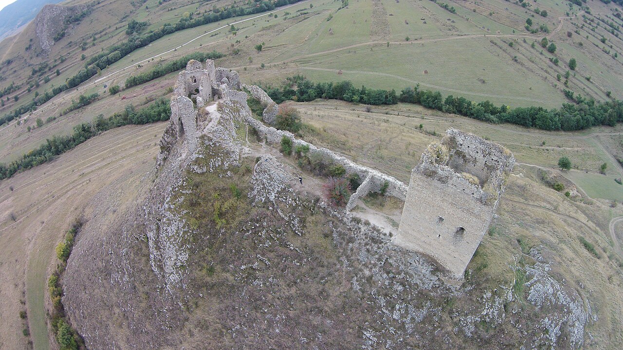 Fotografie aeriană oblică a ruinelor, donjonului, zidurilor și stâncii.
