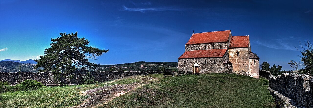 Biserica pe platoul fortificat, cu accesul și zidul de incintă.